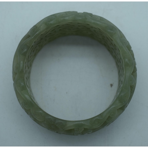 1131 - A CHINESE CARVED JADE RETICULATED BANGLE. 95 grams. 5.75 cm wide internally.