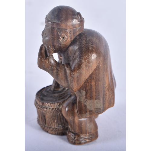 1353 - A Japanese Carved Hardwood Netsuke in the form of a Seated Male stirring a cooking pot.  5.5 cm x 3.... 