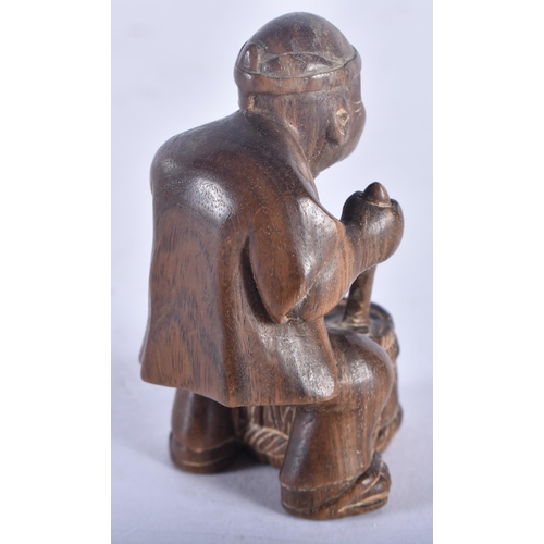 1353 - A Japanese Carved Hardwood Netsuke in the form of a Seated Male stirring a cooking pot.  5.5 cm x 3.... 