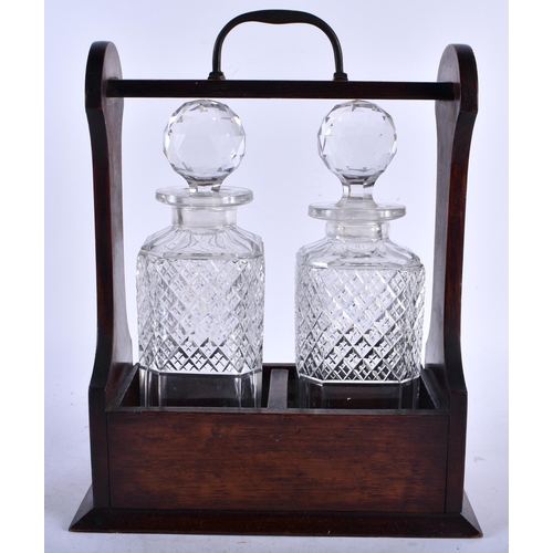 550 - AN EDWARDIAN OAK TWO GLASS TANTALUS. 32 cm x 18 cm.