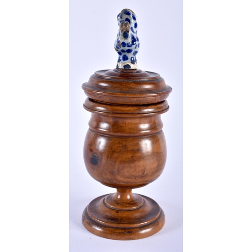 585 - AN 18TH/19TH CENTURY CARVED TREEN VASE AND COVER with 18th century Delft pottery finial. 24 cm high.