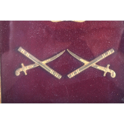 619 - A FRAMED MILITARY BADGE. 24 cm x 18 cm.