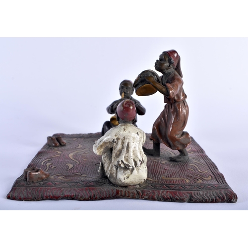 621 - A CONTINENTAL COLD PAINTED BRONZE FIGURAL GROUP modelled as three figures upon a rug. 15 cm square.