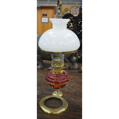 750 - A LARGE BRASS AND CRANBERRY GLASS ADJUSTABLE OIL LAMP. 62 cm high.