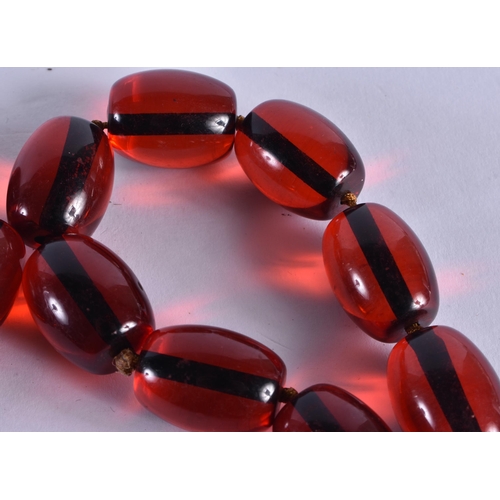 1043 - A LARGE CHERRY AMBER TYPE NECKLACE. 205 grams. 88 cm long, each bead 2.75 cm x 2 cm.