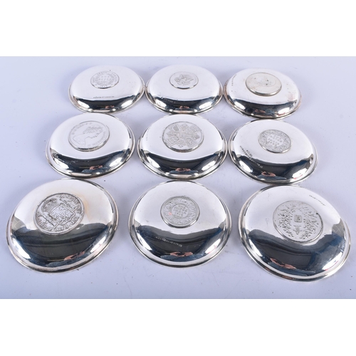 1116 - A SET OF WAIKEE SILVER COIN INSET DISHES. 482 grams. 9 cm diameter. (qty)