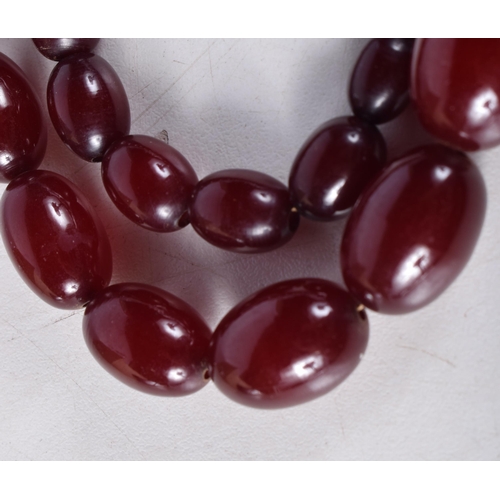 1606 - A CHERRY AMBER NECKLACE. 72 grams. 68 cm long, largest bead 2.75 cm x 1.75 cm.