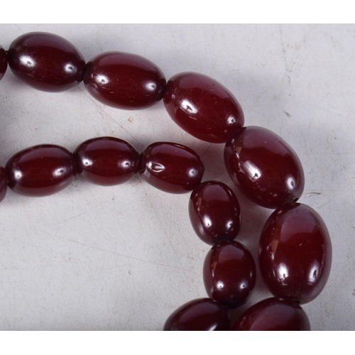 1606 - A CHERRY AMBER NECKLACE. 72 grams. 68 cm long, largest bead 2.75 cm x 1.75 cm.