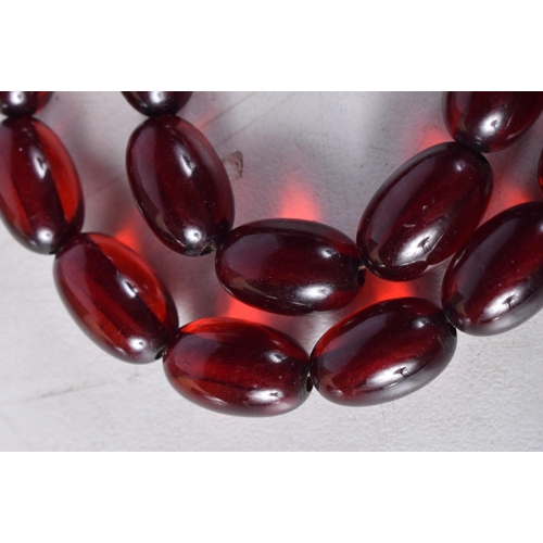 1610 - A CHERRY AMBER TYPE NECKLACE. 23 grams. 55 cm long, each bead 1 cm x 0.5 cm.