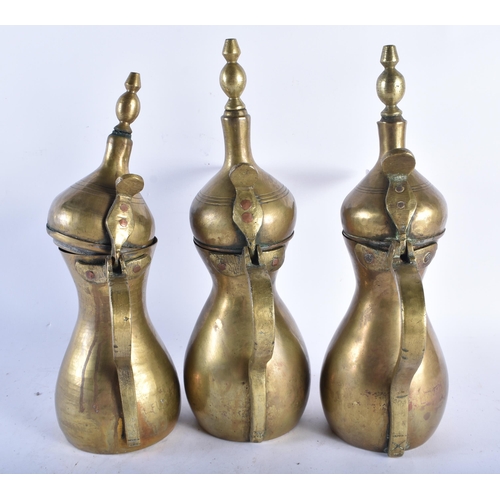 593 - THREE ANTIQUE MIDDLE EASTERN BRASS COFFEE POTS two with impressed seals. Largest 32 cm high. (3)