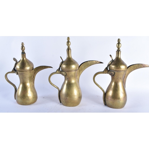 593 - THREE ANTIQUE MIDDLE EASTERN BRASS COFFEE POTS two with impressed seals. Largest 32 cm high. (3)