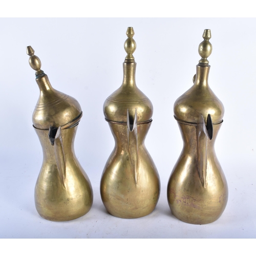 593 - THREE ANTIQUE MIDDLE EASTERN BRASS COFFEE POTS two with impressed seals. Largest 32 cm high. (3)