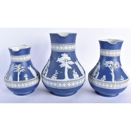 677 - A GRADUATED SET OF THREE ANTIQUE WEDGWOOD JASPERWARE JUGS. Largest 20 cm x 12 cm. (3)