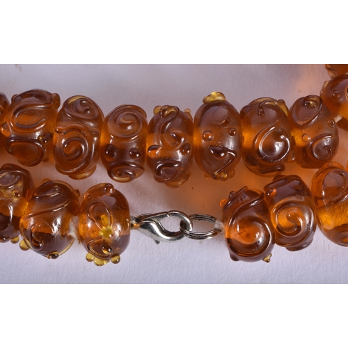 701 - A CHINESE REPUBLICAN PERIOD PEKING AMBER GLASS NECKLACE. 52 cm long.