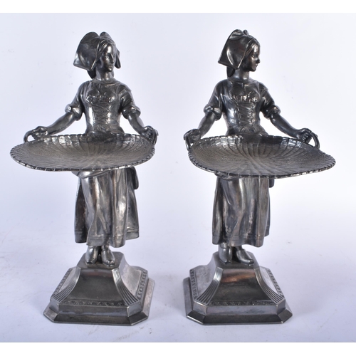 707 - A PAIR OF EARLY 20TH CENTURY WMF PEWTER SWEETMEAT FIGURAL DISHES modelled as females holding out fla... 