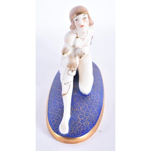 877 - AN ART DECO PORCELAIN FIGURE OF A NUDE FEMALE modelled holding a bird. 13 cm wide.