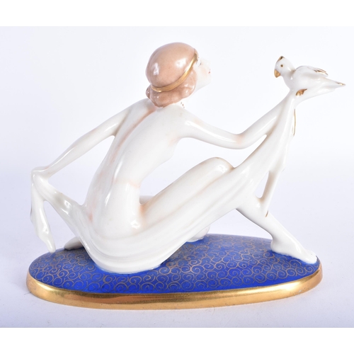 877 - AN ART DECO PORCELAIN FIGURE OF A NUDE FEMALE modelled holding a bird. 13 cm wide.