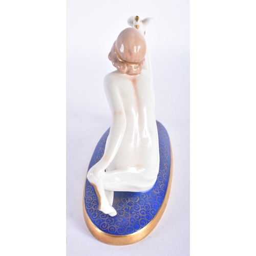 877 - AN ART DECO PORCELAIN FIGURE OF A NUDE FEMALE modelled holding a bird. 13 cm wide.