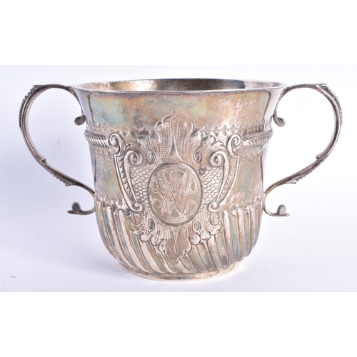 298 - AN EARLY ENGLISH TWIN HANDLED SILVER REPOUSSE PORRINGER decorated with an acanthus capped monogram. ... 