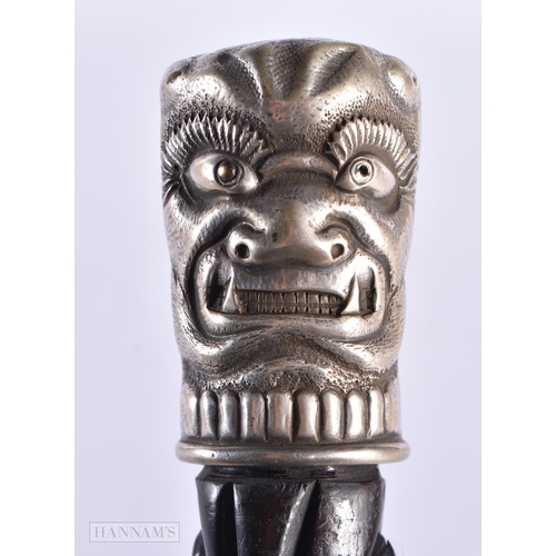 12 - AN UNUSUAL ANTIQUE SILVER MOUNTED TRIBAL MASK HARDWOOD WALKING CANE. 90 cm long.