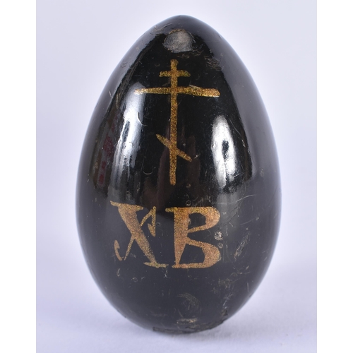 146 - A 19TH CENTURY RUSSIAN BLACK LACQUER EGG painted with a religious building. 7.5 cm x 4.5 cm.