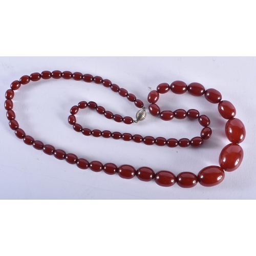 1322 - A CHERRY AMBER TYPE NECKLACE. 52 grams. 70 cm long, largest bead 2.5 cm x 1.75 cm.