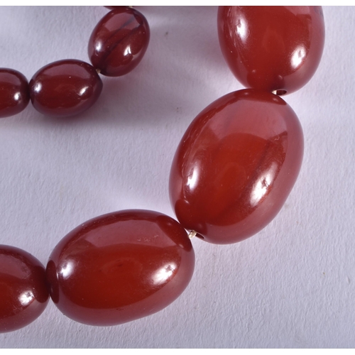 1322 - A CHERRY AMBER TYPE NECKLACE. 52 grams. 70 cm long, largest bead 2.5 cm x 1.75 cm.