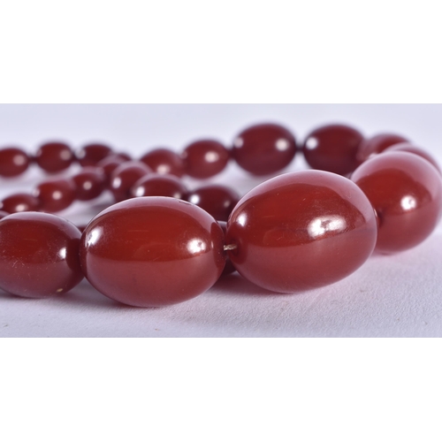 1322 - A CHERRY AMBER TYPE NECKLACE. 52 grams. 70 cm long, largest bead 2.5 cm x 1.75 cm.