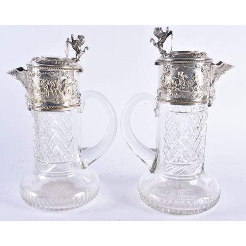 1387 - A PAIR OF ANTIQUE SILVER PLATED CUT GLASS CLARET JUGS formed with heraldic lions, decorated with fig... 