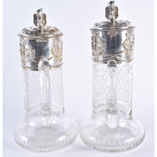 1387 - A PAIR OF ANTIQUE SILVER PLATED CUT GLASS CLARET JUGS formed with heraldic lions, decorated with fig... 