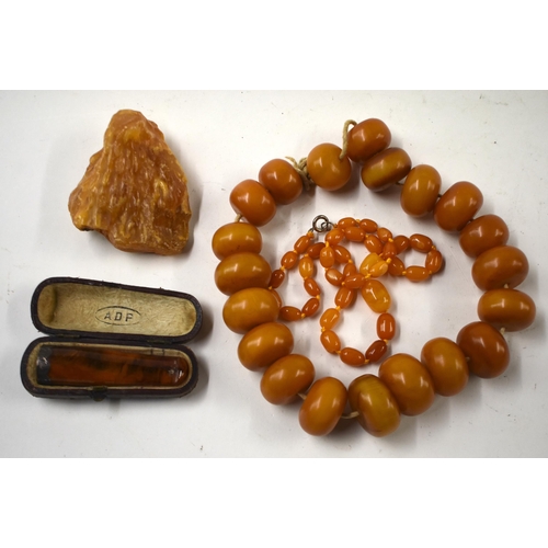 863 - TWO AMBER NECKLACES together with a cheroot holder & a boulder. (4)