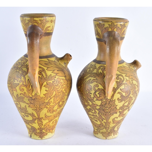 231 - A PAIR OF ART NOUVEAU TWIN HANDLED POTTERY EWERS painted with flowers. 28 cm x 14 cm.