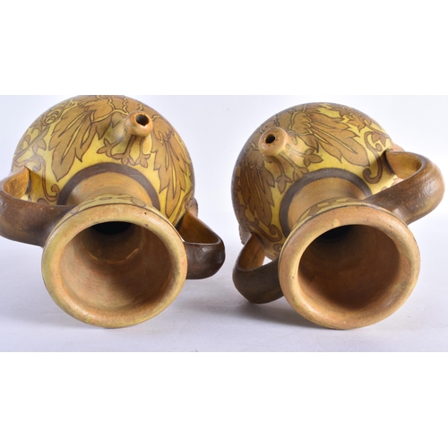 231 - A PAIR OF ART NOUVEAU TWIN HANDLED POTTERY EWERS painted with flowers. 28 cm x 14 cm.