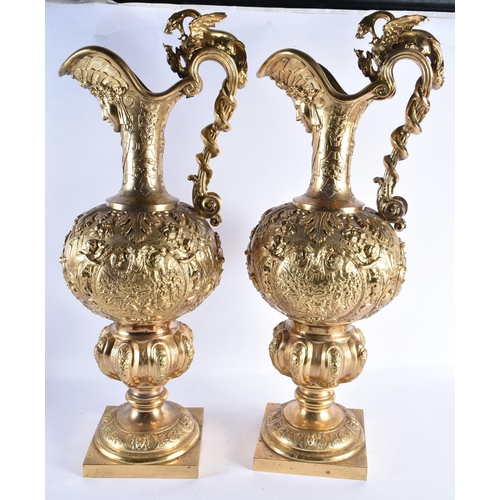 233 - A LARGE PAIR OF 19TH CENTURY FRENCH GILT BRONZE EWERS decorated in relief with classical figures and... 