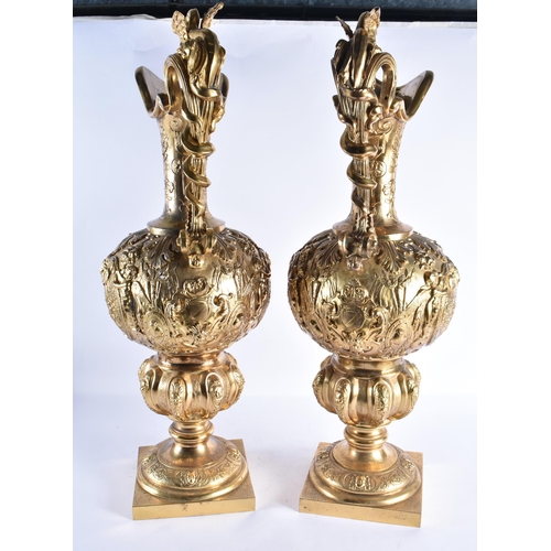 233 - A LARGE PAIR OF 19TH CENTURY FRENCH GILT BRONZE EWERS decorated in relief with classical figures and... 