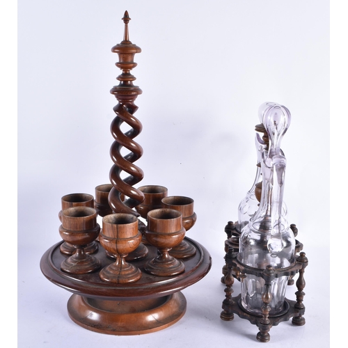 246 - AN ANTIQUE TREEN EGG CUP HOLDER together with a treen carved wood liquor set. Largest 40 cm high. (2... 