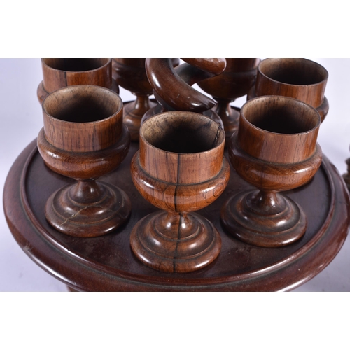 246 - AN ANTIQUE TREEN EGG CUP HOLDER together with a treen carved wood liquor set. Largest 40 cm high. (2... 