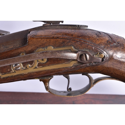 272 - AN ANTIQUE PISTOL  upon a stand. 38 cm wide.