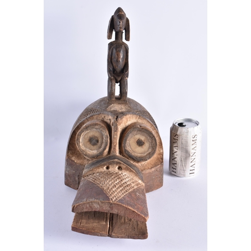 382 - AN UNUSUAL AFRICAN TRIBAL CARVED WOOD BIRD HEAD MASK modelled with an attendant standing upon its he... 