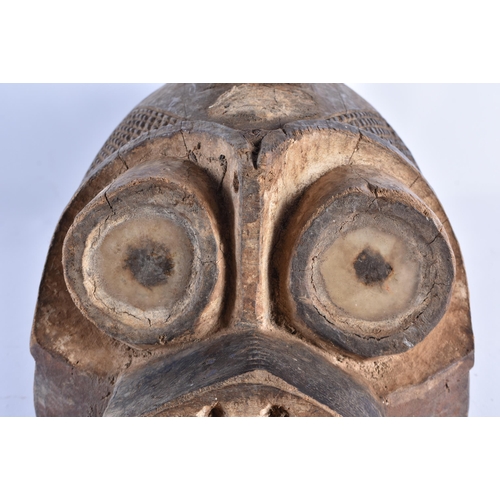 382 - AN UNUSUAL AFRICAN TRIBAL CARVED WOOD BIRD HEAD MASK modelled with an attendant standing upon its he... 