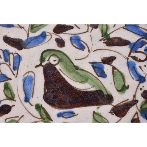 56 - A 17TH/18TH CENTURY PERSIAN IZNIK POTTERY DISH painted with a bird amongst foliage. 16 cm diameter.