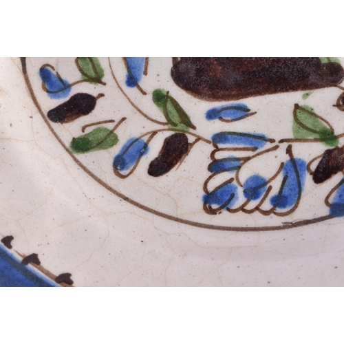 56 - A 17TH/18TH CENTURY PERSIAN IZNIK POTTERY DISH painted with a bird amongst foliage. 16 cm diameter.