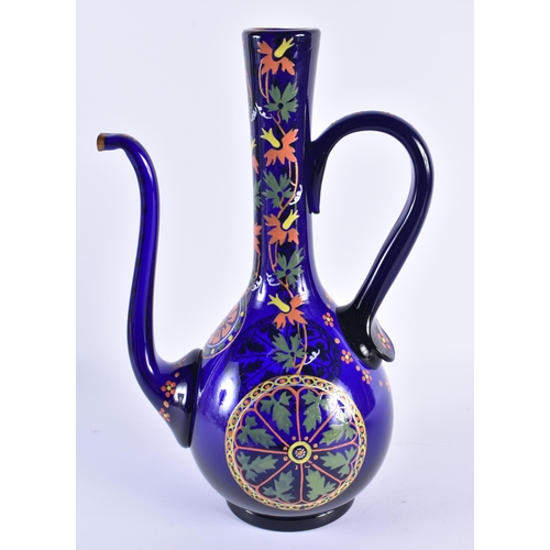 60 - AN EARLY 20TH CENTURY CONTINENAL IZNIK STYLE ENAMELLED BLUE GLASS EWER decorated with foliage. 37 cm... 