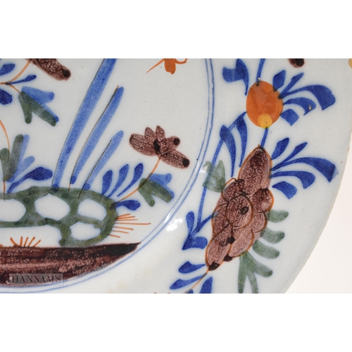 866 - Mid 18th century Lambeth polychrome plate painted with a large flower, smaller flowers, leaves and h... 