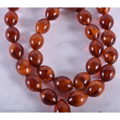 1955 - AN AMBER TYPE NECKLACE. 21 grams. 72 cm long, largest bead 4.5 cm long.