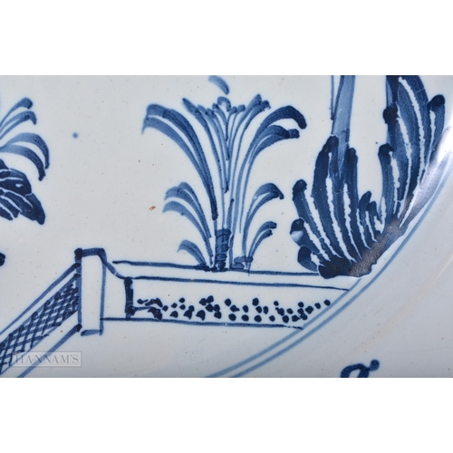 317 - A LARGE 18TH CENTURY DELFT BLUE AND WHITE TIN GLAZED DISH painted with birds and a fenced garden. 30... 