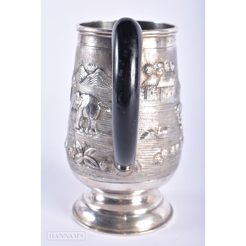 574 - AN INDIAN SILVER REPOUSSE MUG. 285 grams. 15cm high.