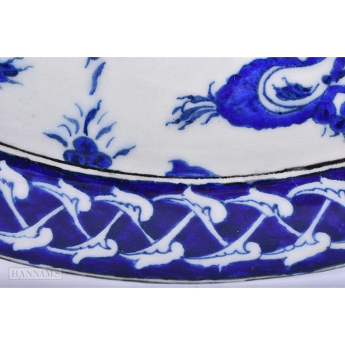 643 - A TURKISH OTTOMAN IZNIK POTTERY PLATE painted with a stylised tree. 33cm wide.