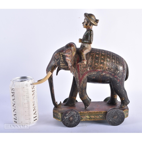 99 - AN ANTIQUE INDIAN PAINTED WOOD TOY modelled as an elephant with attendant. 27cm x 18cm.