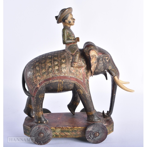 99 - AN ANTIQUE INDIAN PAINTED WOOD TOY modelled as an elephant with attendant. 27cm x 18cm.